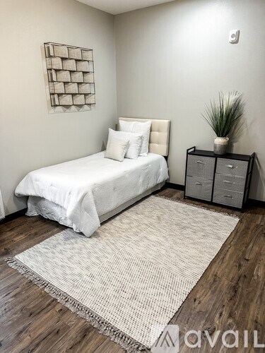 A bedroom with a white bed and a wooden floor.