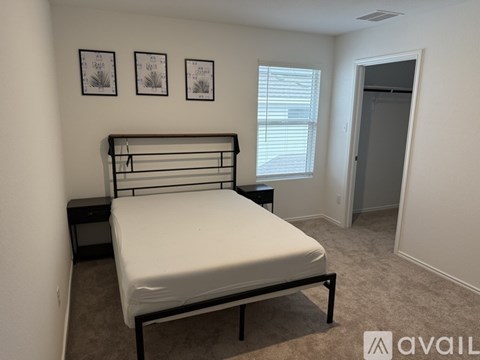 A bedroom with a bed, nightstand, and two pictures on the wall.