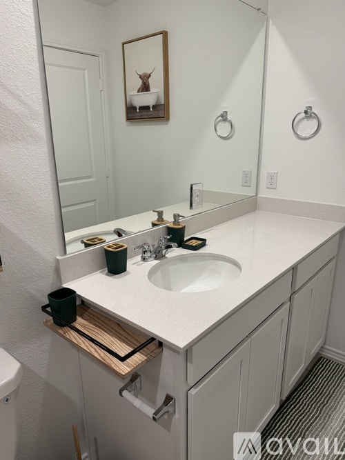 A bathroom with a white counter top and a wooden tray under the mirror.