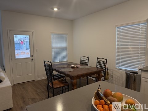 A dining room with a table set for four and a bowl of fruit on the table.