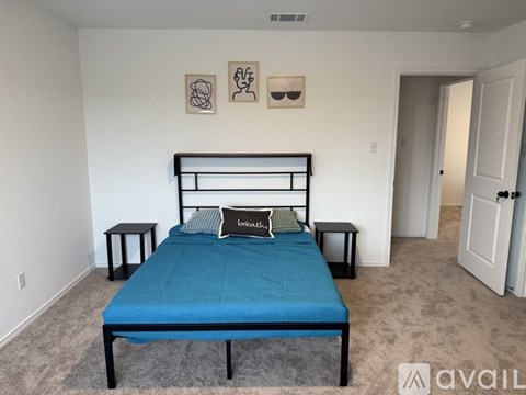 A bedroom with a blue bedspread and a black metal bed frame.