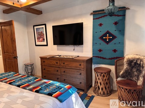 A bedroom with a bed, dresser, and a wall hanging.