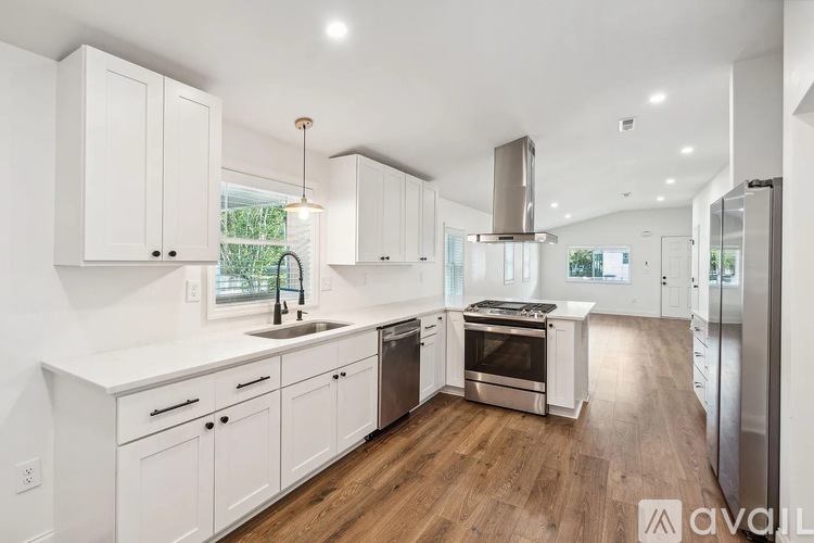 A modern kitchen with white cabinets and stainless steel appliances.