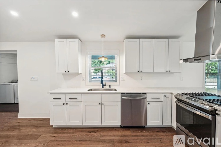 A kitchen with white cabinets and a window.