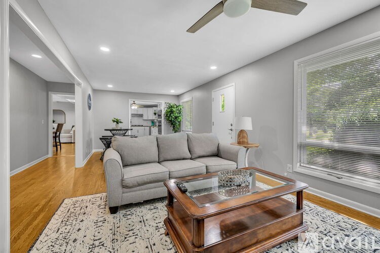 A living room with a grey couch, a coffee table, and a ceiling fan.
