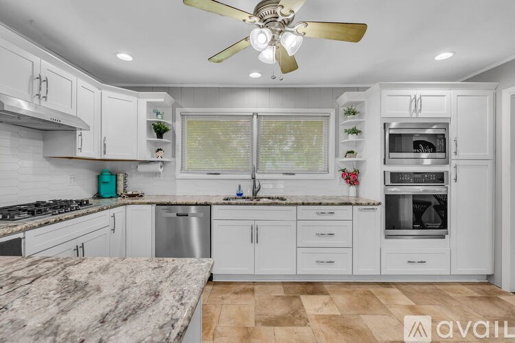 A kitchen with white cabinets and a marble countertop.