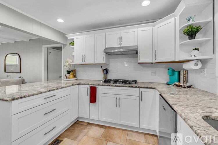 A kitchen with white cabinets and a marble countertop.