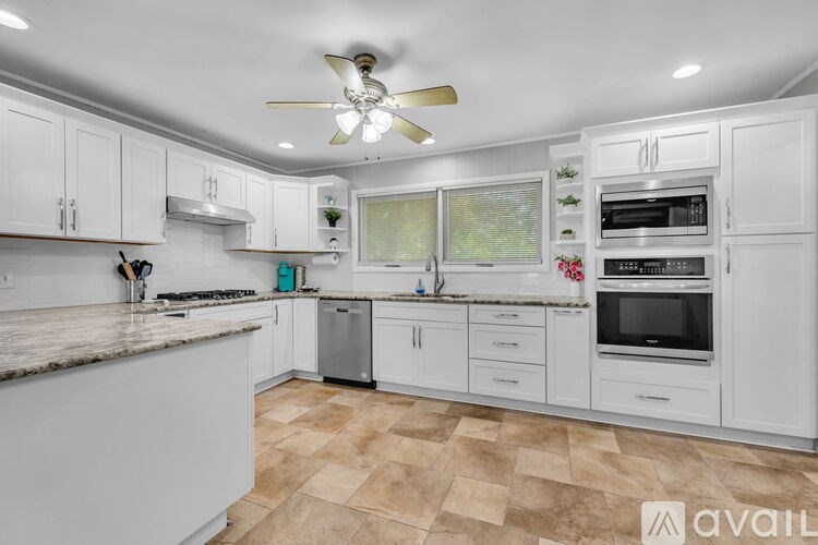 A kitchen with white cabinets and a fan on the ceiling.