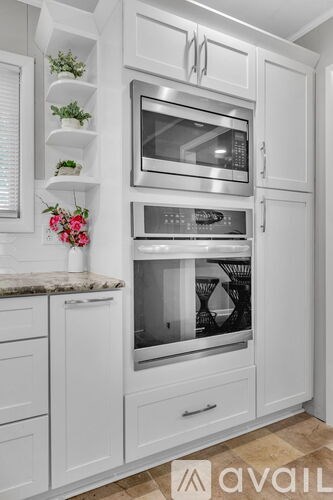 A kitchen with white cabinets and a marble countertop.