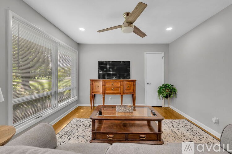 A room with a ceiling fan, a wooden table, and a couch.