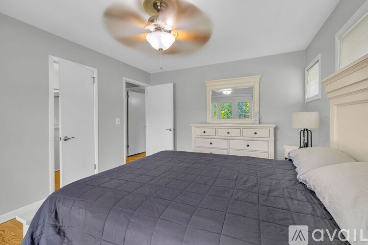 A bedroom with a bed, dresser, and ceiling fan.