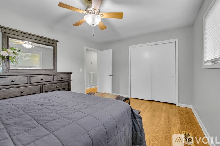 A bedroom with a bed, dresser, and a window with a view.
