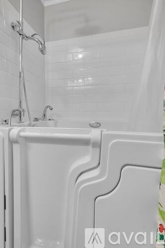 A white bathtub with a shower head and faucet.