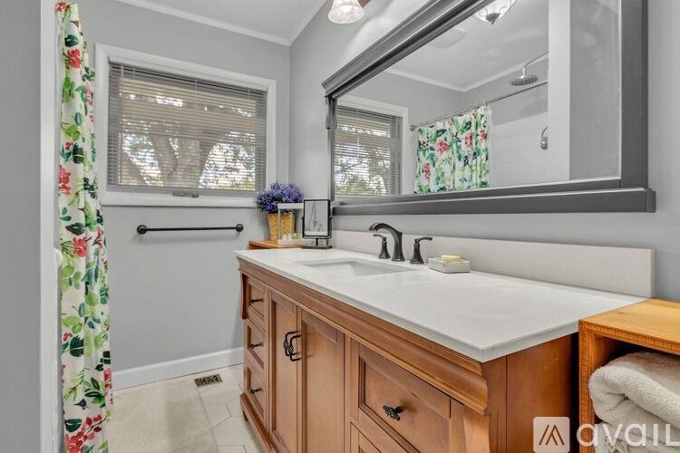 A bathroom with a floral shower curtain and a mirror above a sink.