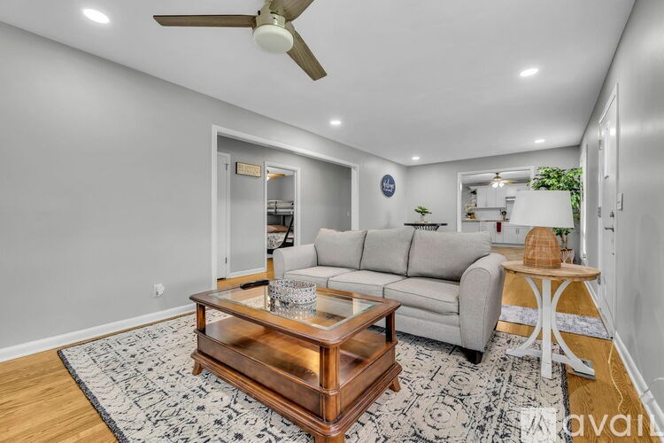 A living room with a grey couch, a wooden coffee table, and a ceiling fan.