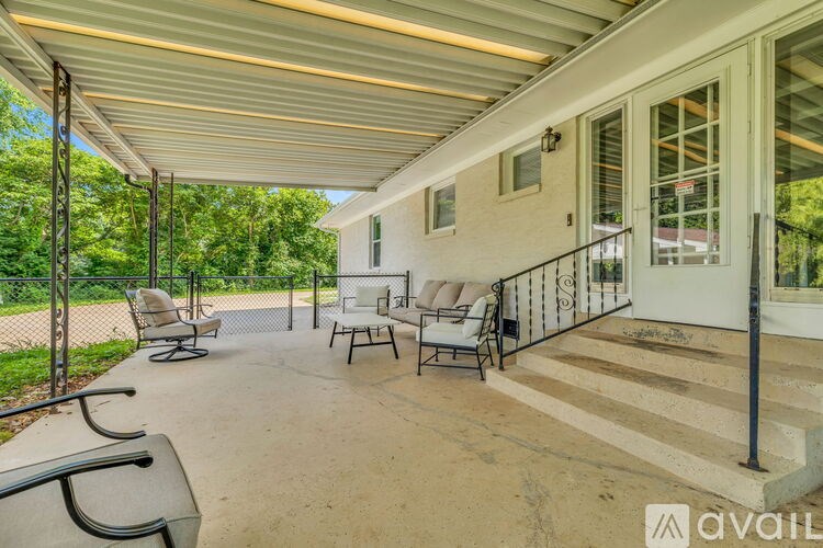 A patio with a white house and a black railing.
