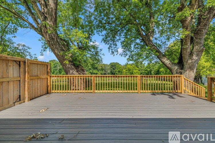 A wooden deck with a railing and trees in the background.
