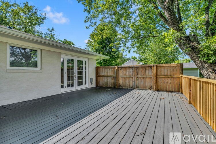 A wooden deck leads to a house with a glass door.