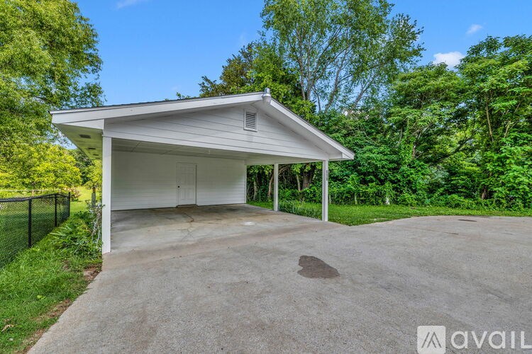 A detached garage with a white roof and a concrete driveway.