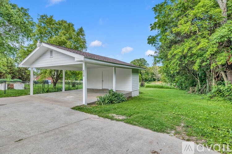 A white covered garage is situated in a grassy area.