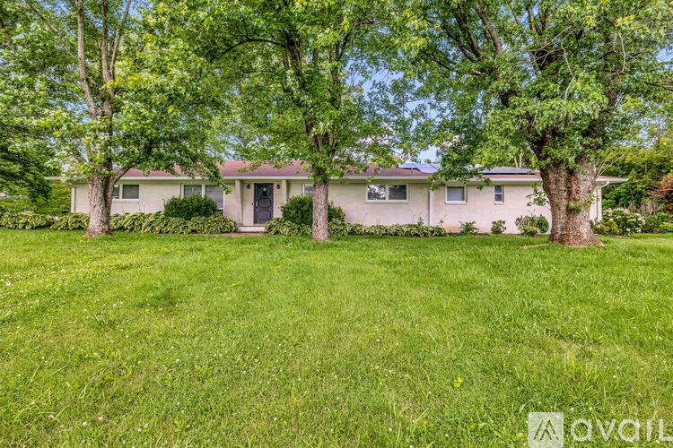 A house with a lawn and trees in front of it.