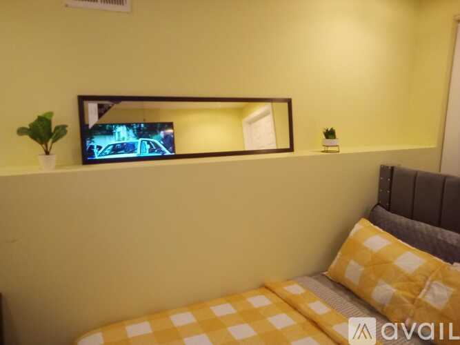 A bedroom with a bed, a mirror, and a small potted plant.