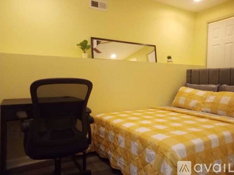 A bedroom with a bed, a chair, and a mirror on the wall.