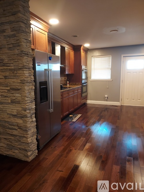 A kitchen with wooden floors and a stone pillar.