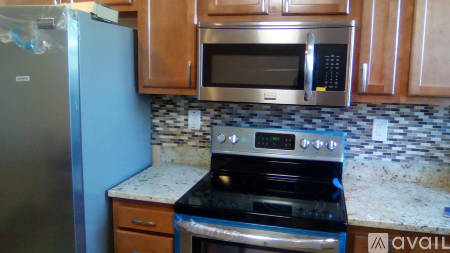 A kitchen with a black stove top oven and a silver microwave above it.