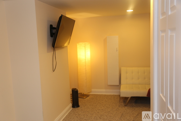 A living room with a white couch and a flat screen TV mounted on the wall.