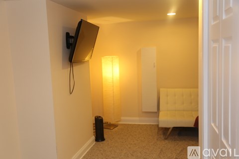 A living room with a white couch and a flat screen TV mounted on the wall.
