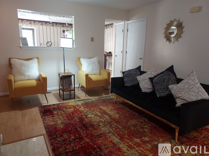 A living room with a black couch and yellow chairs.