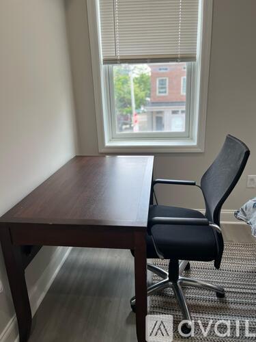 A black chair is placed in front of a window with blinds.