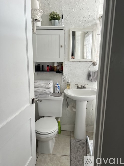 A white bathroom with a toilet, sink, and mirror.