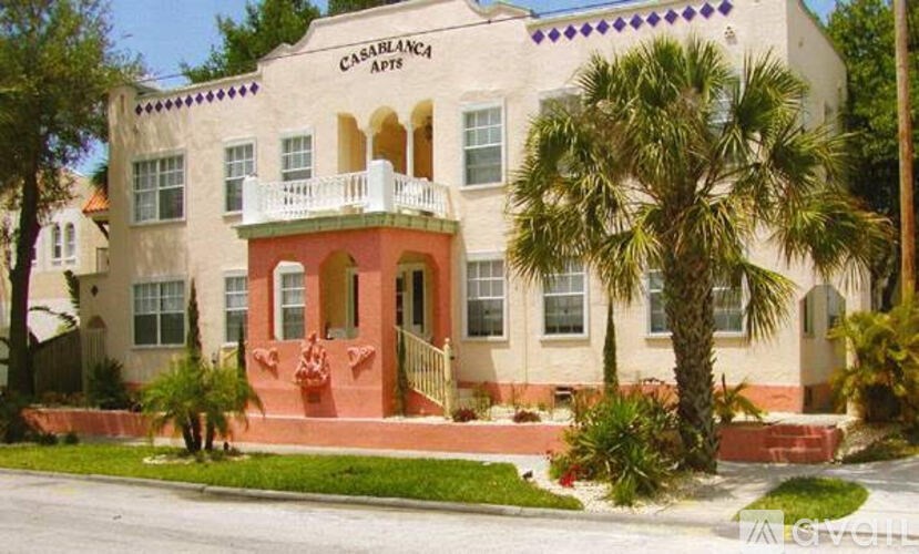 A white building with a balcony and a red door.