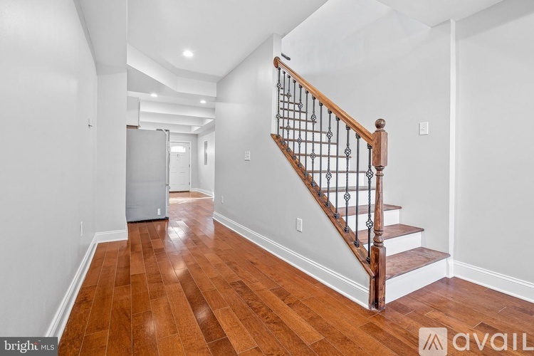 A hallway with a staircase and a refrigerator.