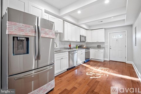 A kitchen with a stainless steel refrigerator and wooden floors.