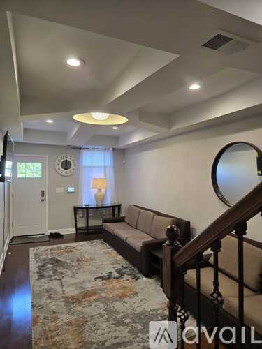 A living room with a couch, a rug, and a mirror on the wall.