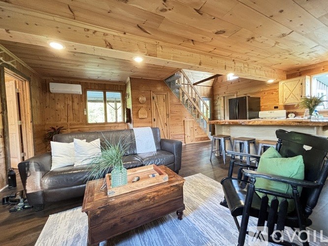 A living room with a wooden ceiling and a staircase.