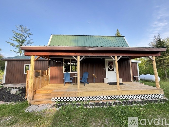 A wooden cabin with a green roof and a deck.