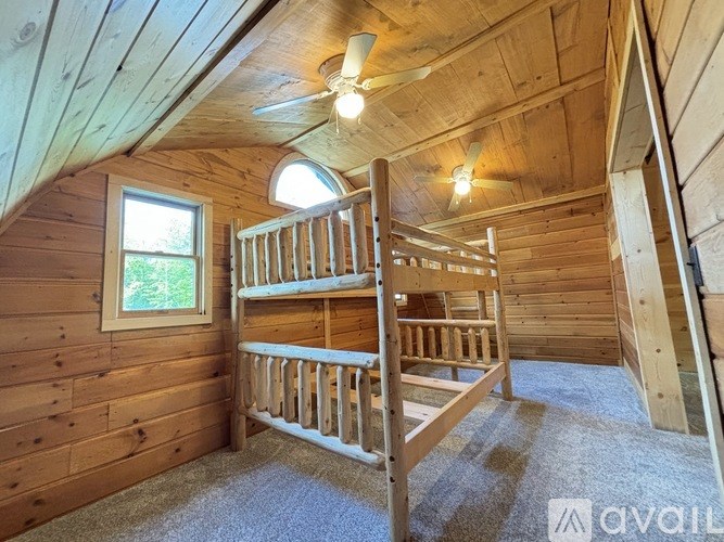 A wooden bunk bed in a room with wooden walls and a window.