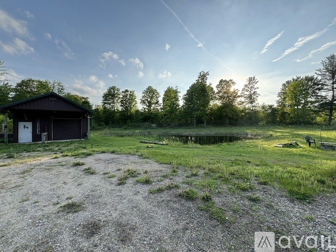 A small building sits in a field with trees in the background.