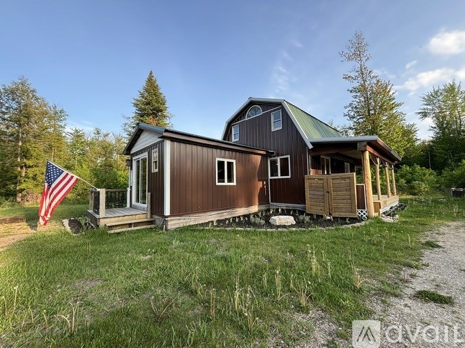 A cabin with a green roof is surrounded by grass and trees.