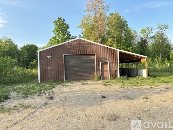 A brown barn with a star on the side is situated in a grassy area.