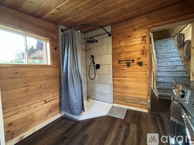 A wooden bathroom with a shower and a window.