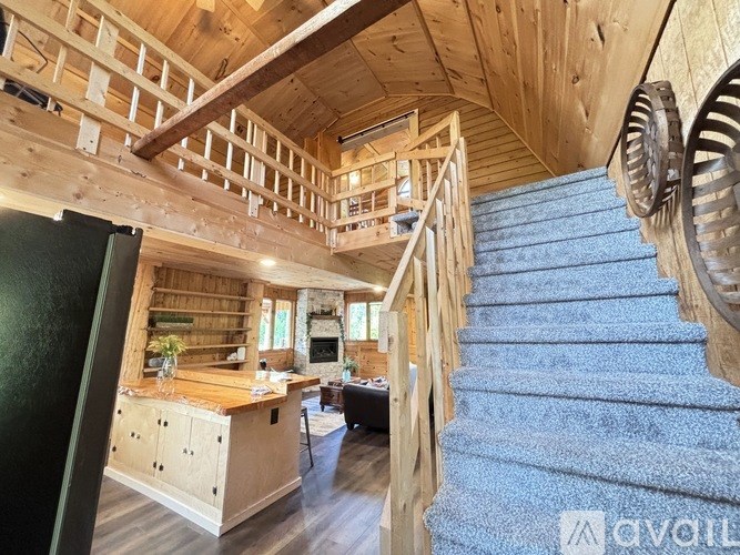 A wooden staircase with a blue carpeted runner leads up to a loft area.