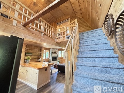 A wooden staircase with a blue carpeted runner leads up to a loft area.