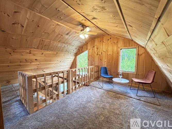 A room with wooden walls and ceiling, a window, and a table with chairs.