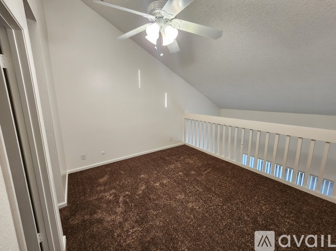 A room with a ceiling fan and carpeted floor.