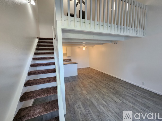 A staircase with a carpeted runner leads up to a second floor landing with a white railing.